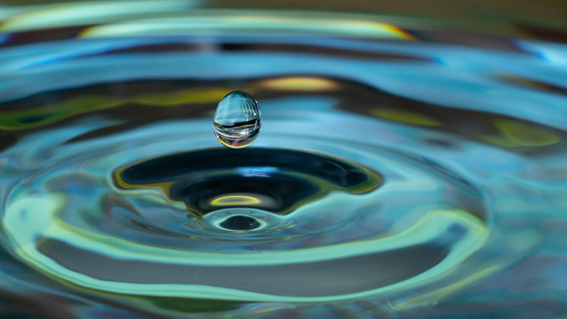 Een waterdruppel die in een wateroppervlak valt en kringen maakt